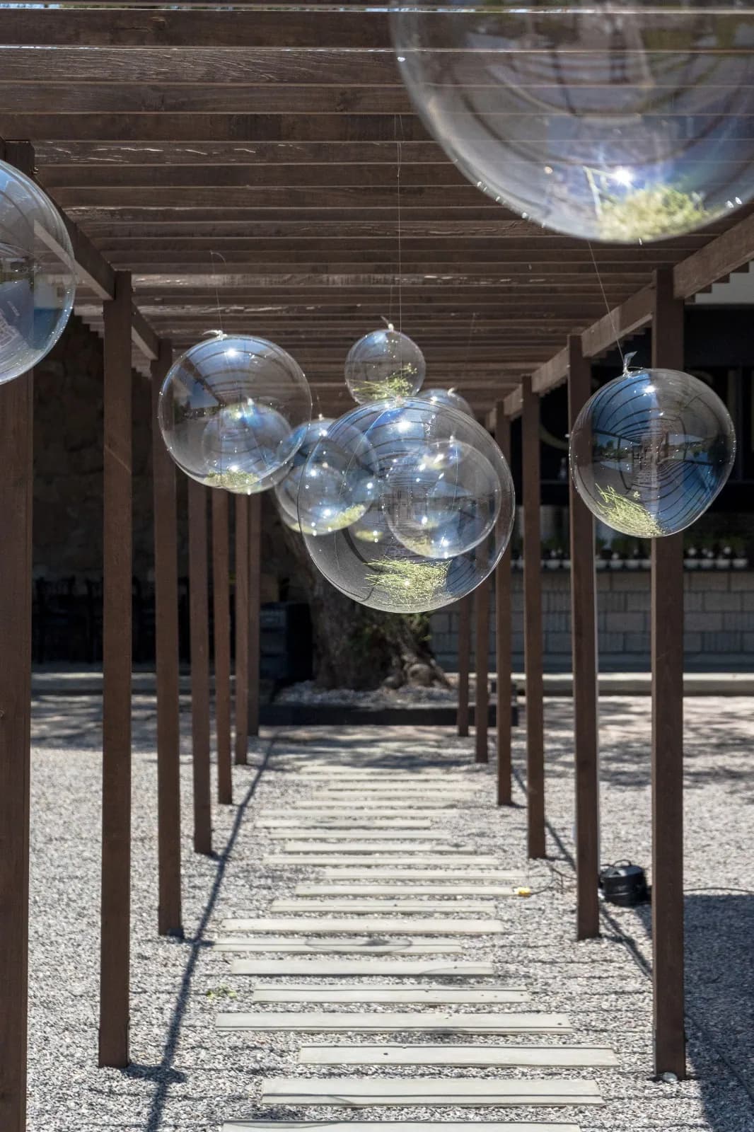 Pasillo bajo la pérgola con esferas transparentes colgantes