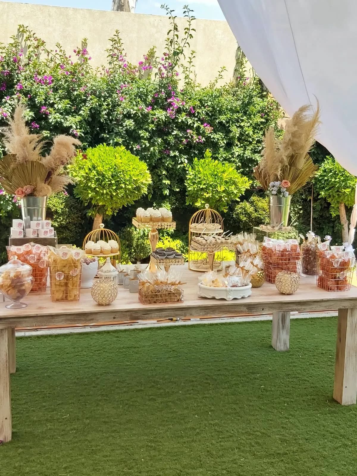 Mesa de dulces con pampas en un jardín