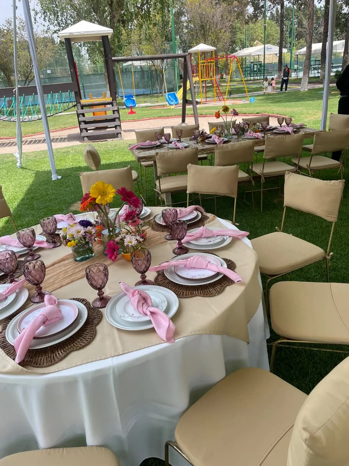 Mesa redonda con mantel blanco y sillas en un jardín